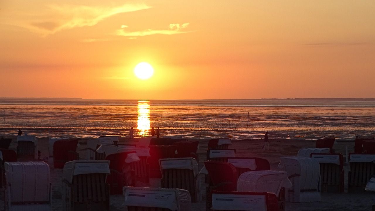 Sonnenuntergang über dem Meer, davor Strandkörbe am Strand von Bensersiel.