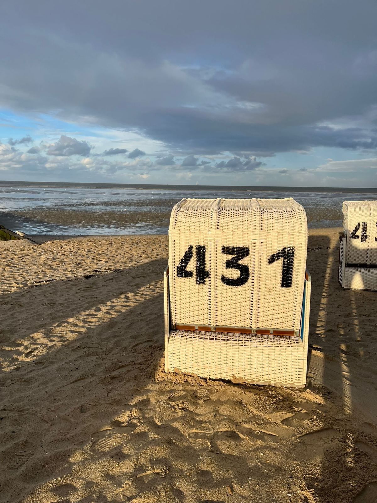 Ein Strandkorb am Hooksieler Strand bei Ebbe mit Blick aufs Watt.