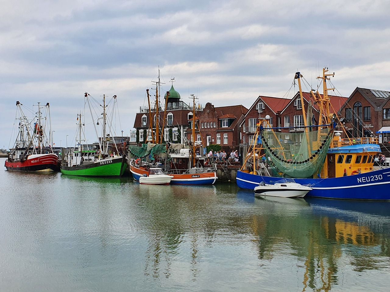 Fischkutter im Hafen von Neuharlingersiel vor der Häuserzeile am Kai.